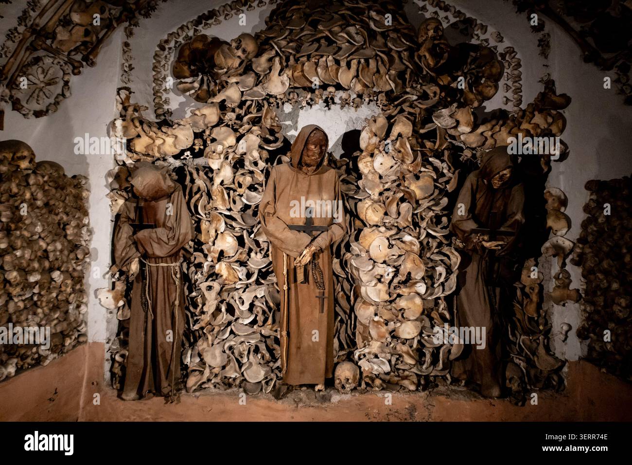 Un moine capucin squelettique vêtu de robes à capuche traditionnelles debout dans la chapelle en os ornée de la crypte capucine à Rome, en Italie. Banque D'Images