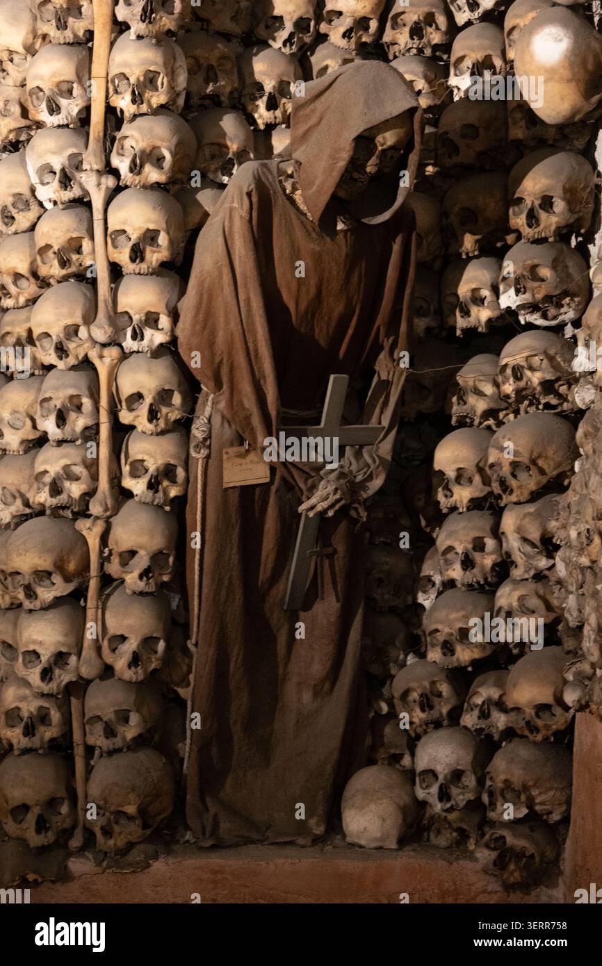 Un moine capucin squelettique vêtu de robes à capuche traditionnelles debout dans la chapelle en os ornée de la crypte capucine à Rome, en Italie. Banque D'Images