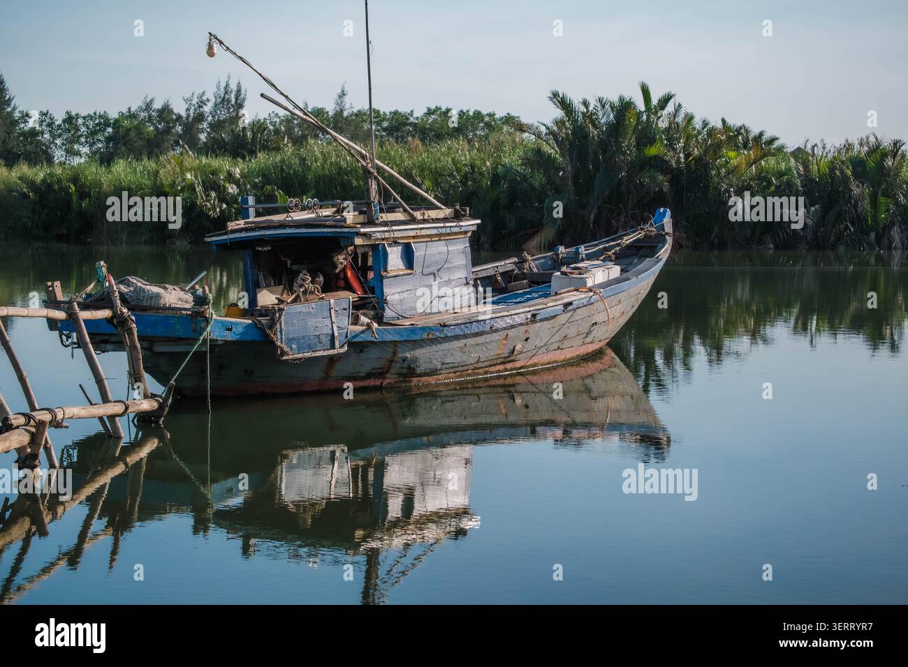 Vieux bateau de pêche en bois vieilli flottant sur une rivière tropicale calme Banque D'Images