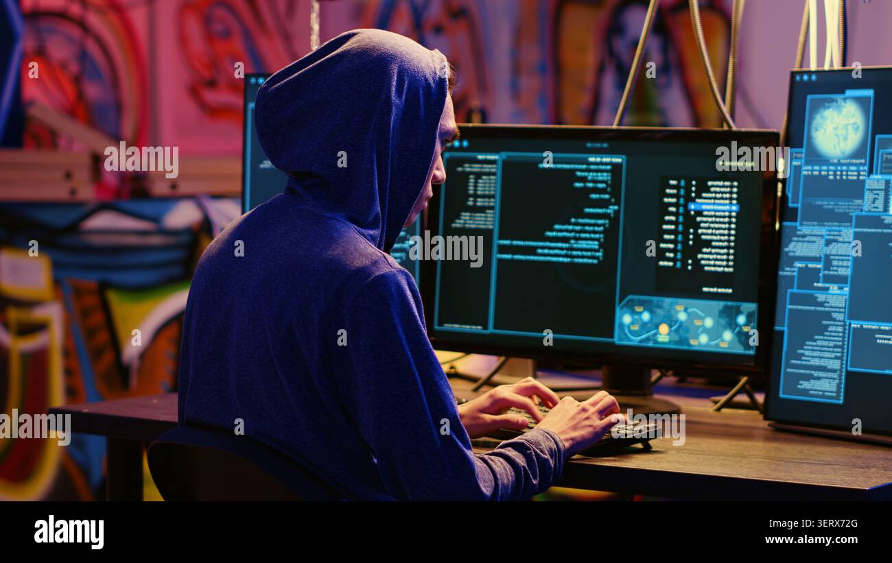 Hacker dans graffiti caché base écriture de lignes de code sur l'ordinateur, développant des logiciels malveillants qui passent devant les systèmes de sécurité, programmeur escroc utilise PC dans bunker, exécutant script de piratage. Banque D'Images