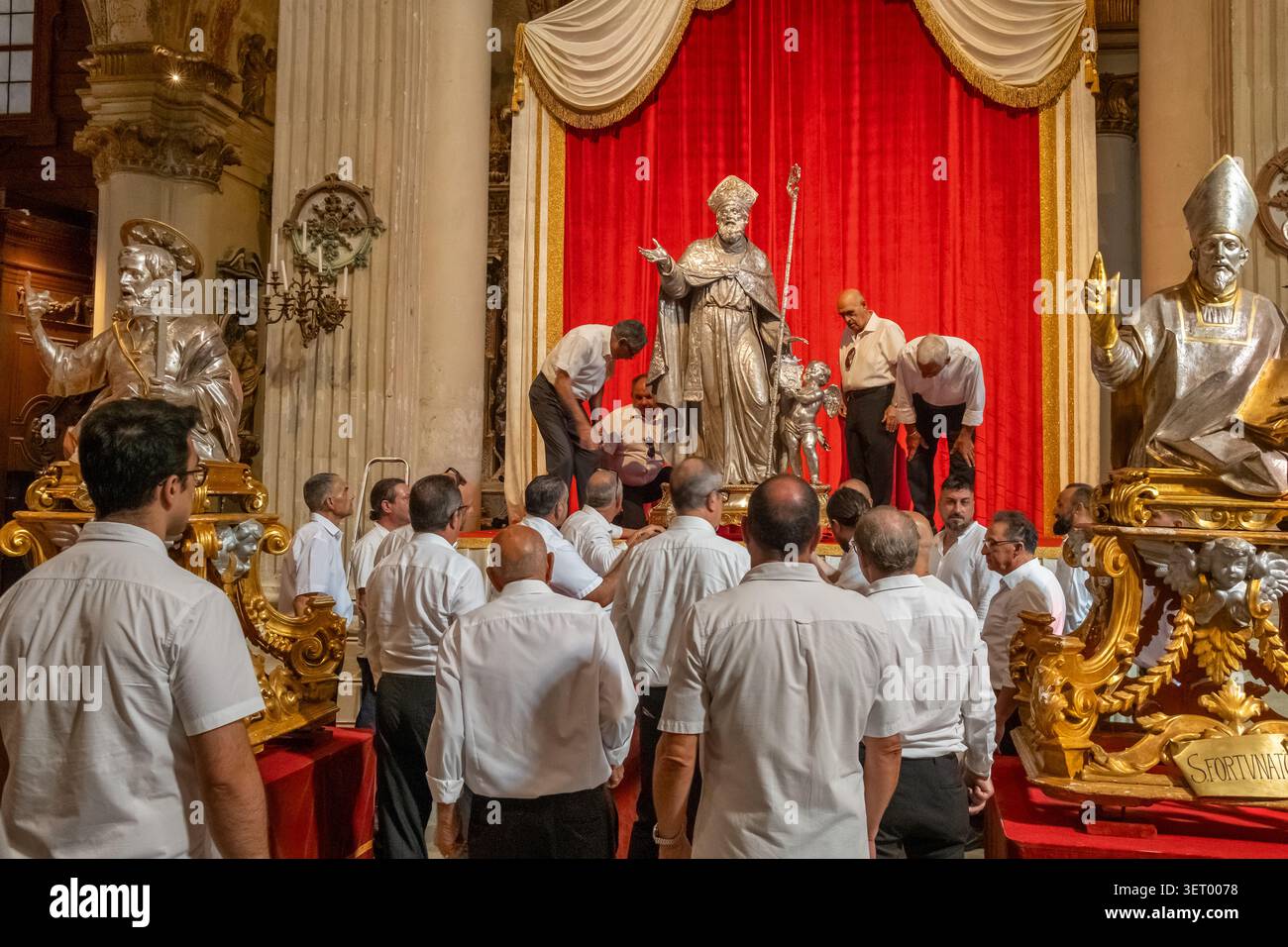 Groupe d'hommes debout près des statues de saint argentées à l'intérieur de la cathédrale de Lecce Banque D'Images