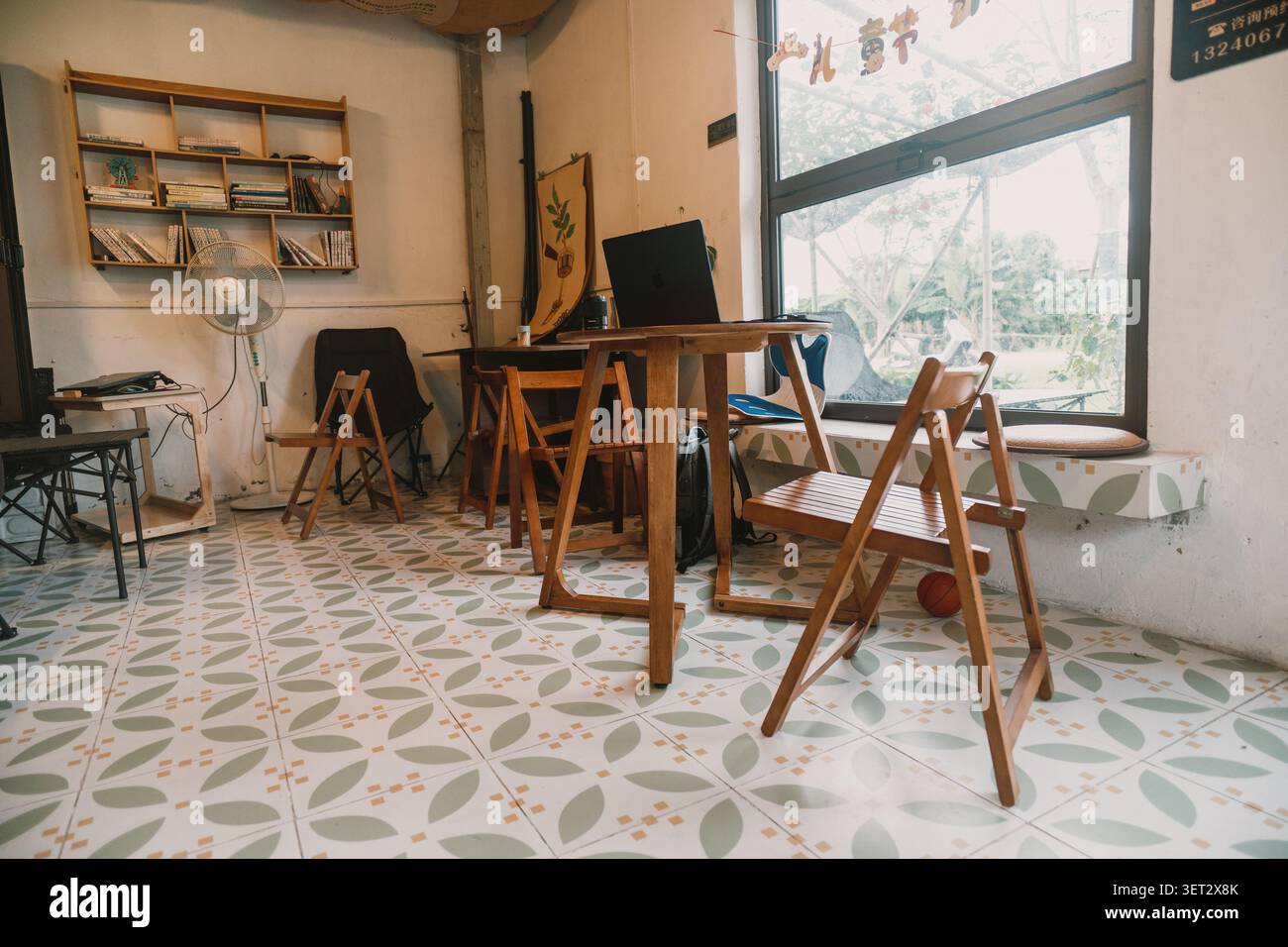 Intérieur de café confortable à Chengdu, Chine - tables en bois, sol en carrelage floral, caractères chinois sur Banque D'Images