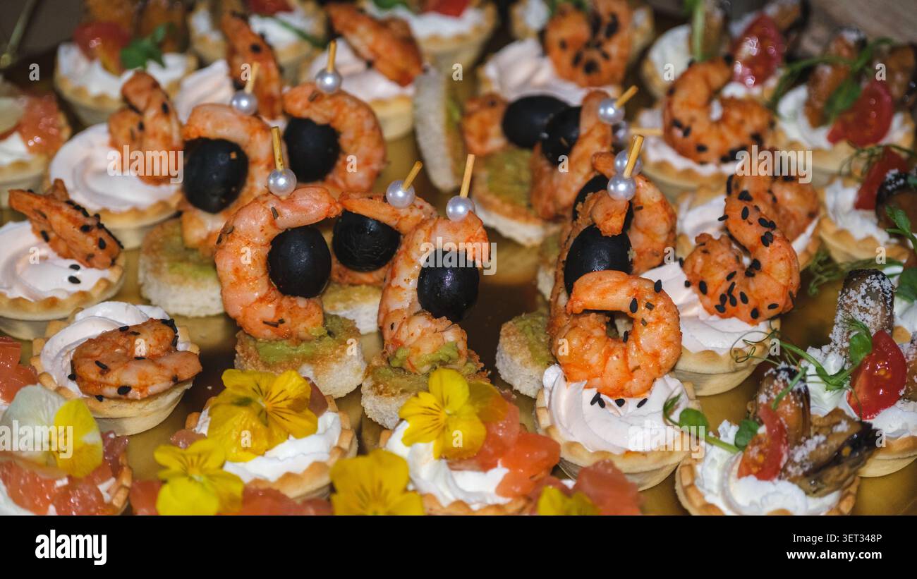 Un assortiment vibrant d'élégants canapés de crevettes servis sur un plateau doré lors d'un événement de restauration haut de gamme dans une atmosphère luxueuse et festive. Banque D'Images