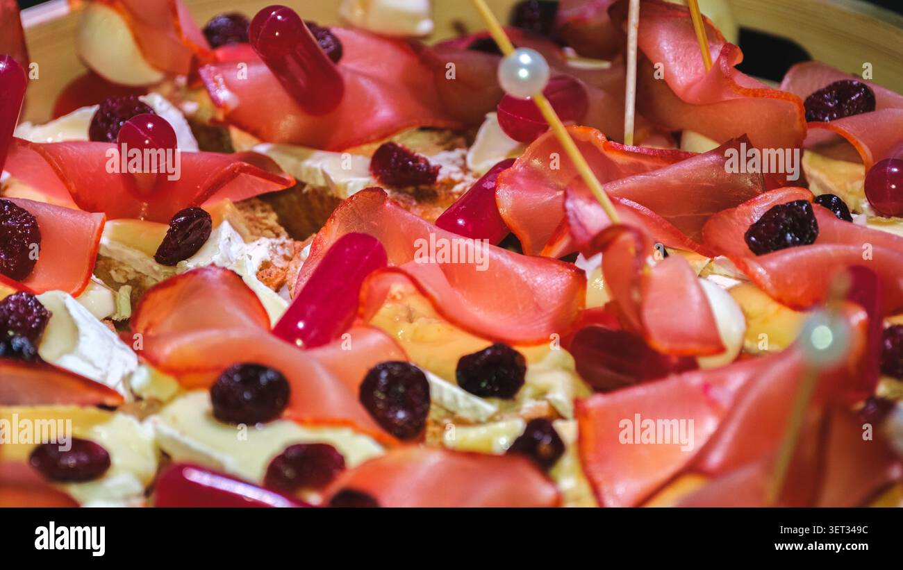 Gros plan sur des hors-d'œuvre artisanaux avec charcuterie, fromage crémeux et baies séchées élégamment préparés pour une fête ou un service sophistiqué Banque D'Images