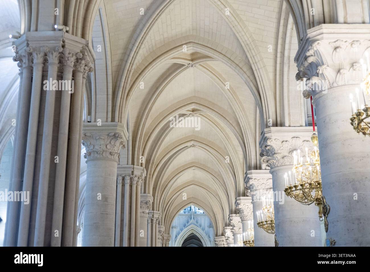 Les visiteurs explorent un grand espace intérieur avec de hautes arches et des colonnes décoratives tandis que la lumière brille à travers l'espace. La conception architecturale capture un Banque D'Images
