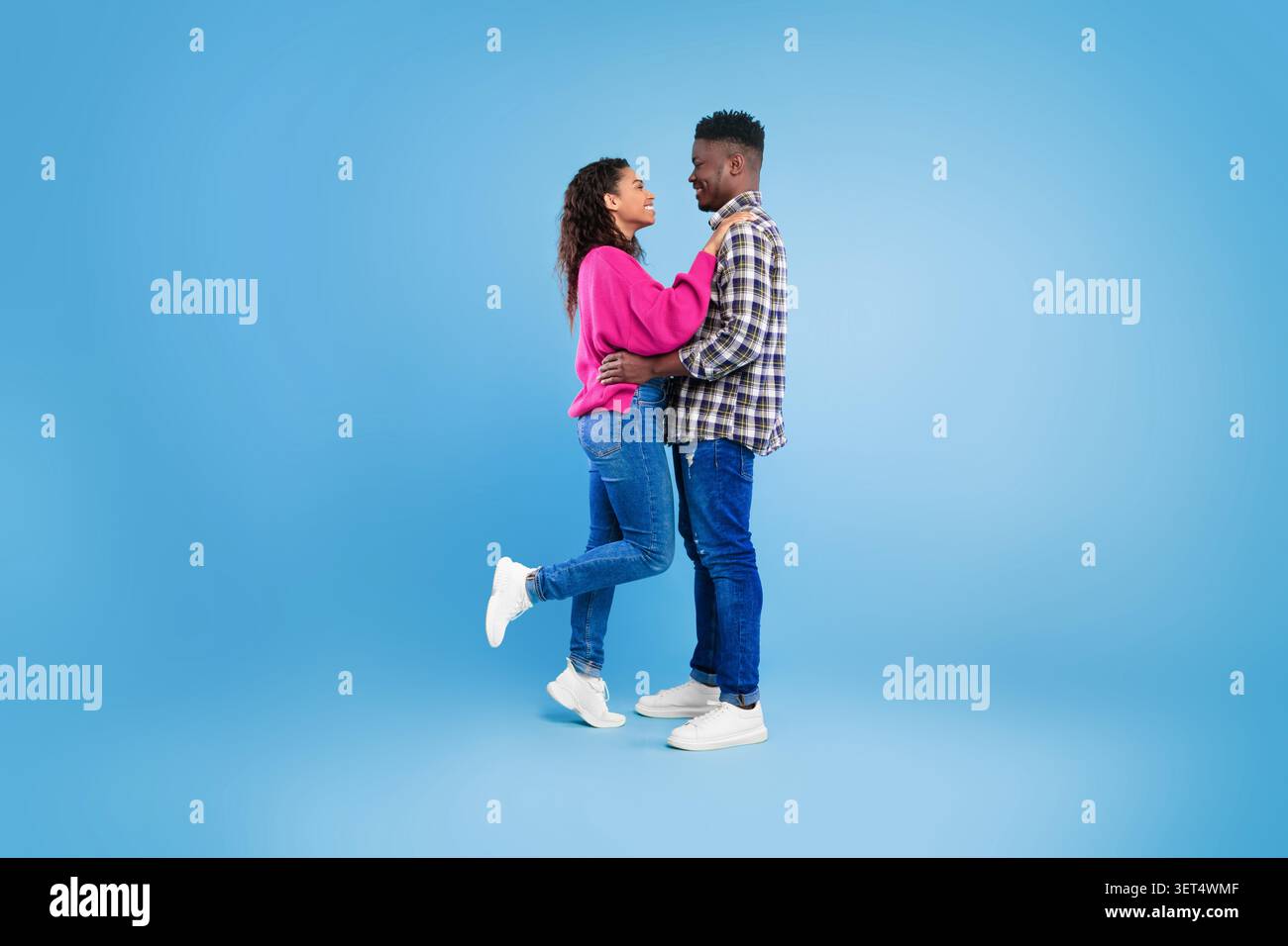 Heureux jeune couple embrassant et souriant ensemble, fond de studio, concept d'amour Banque D'Images