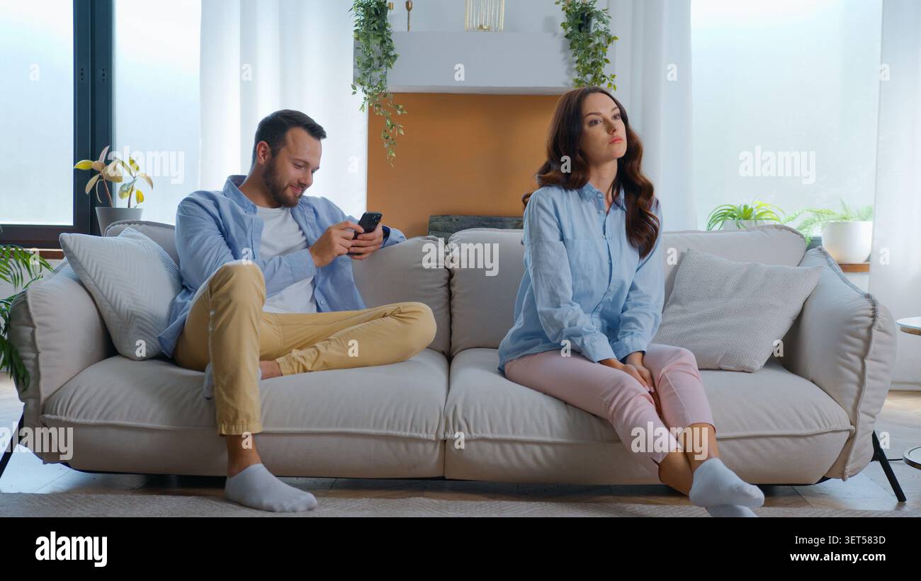 Agacé insatisfait femme caucasienne offensé assis près de l'homme occupé avec téléphone portable gadget accros riant en regardant la vidéo humoristique rire smartphone Banque D'Images