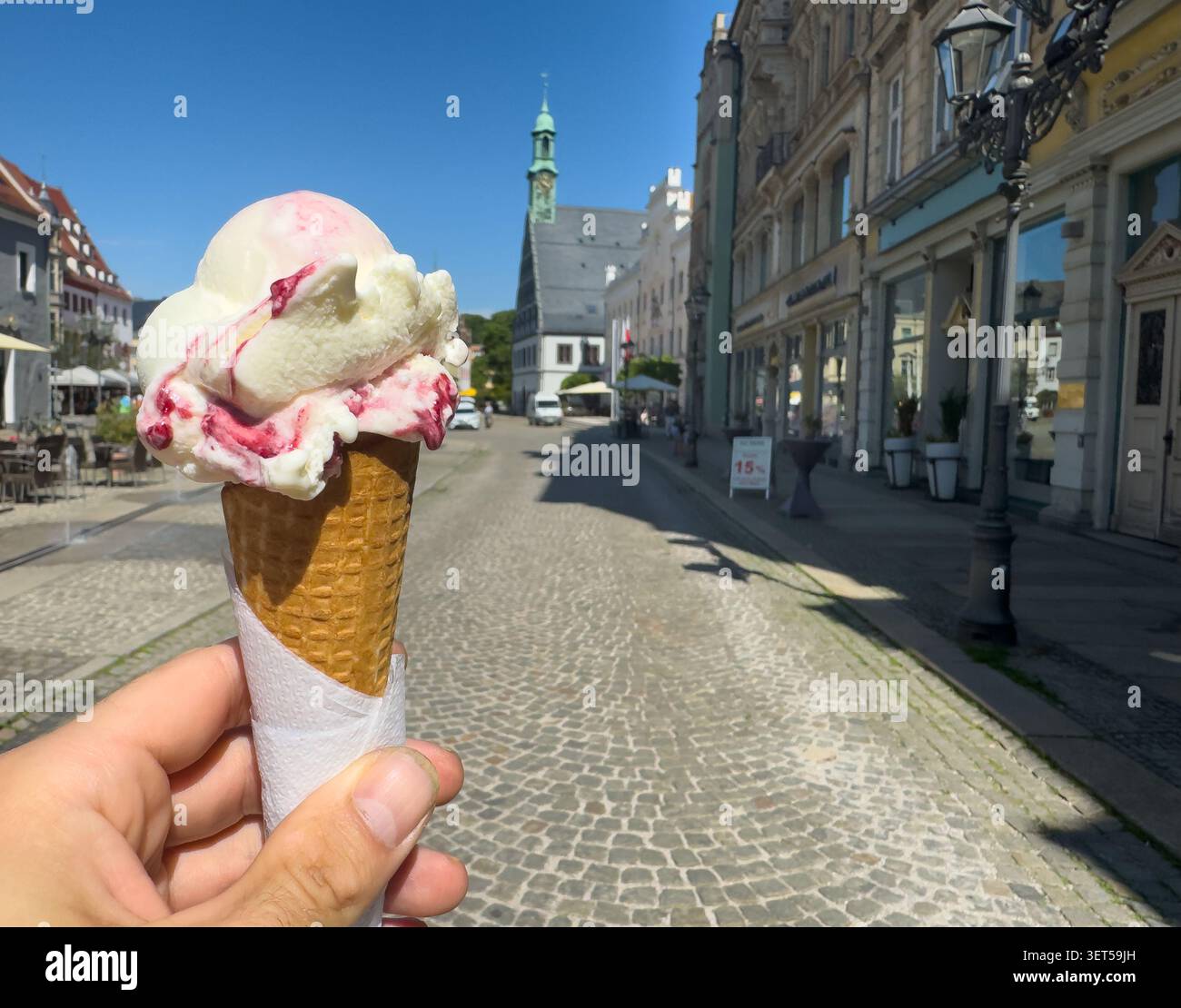 Tenir et manger un gelato dans un cône alors que dehors dans une ville. Banque D'Images