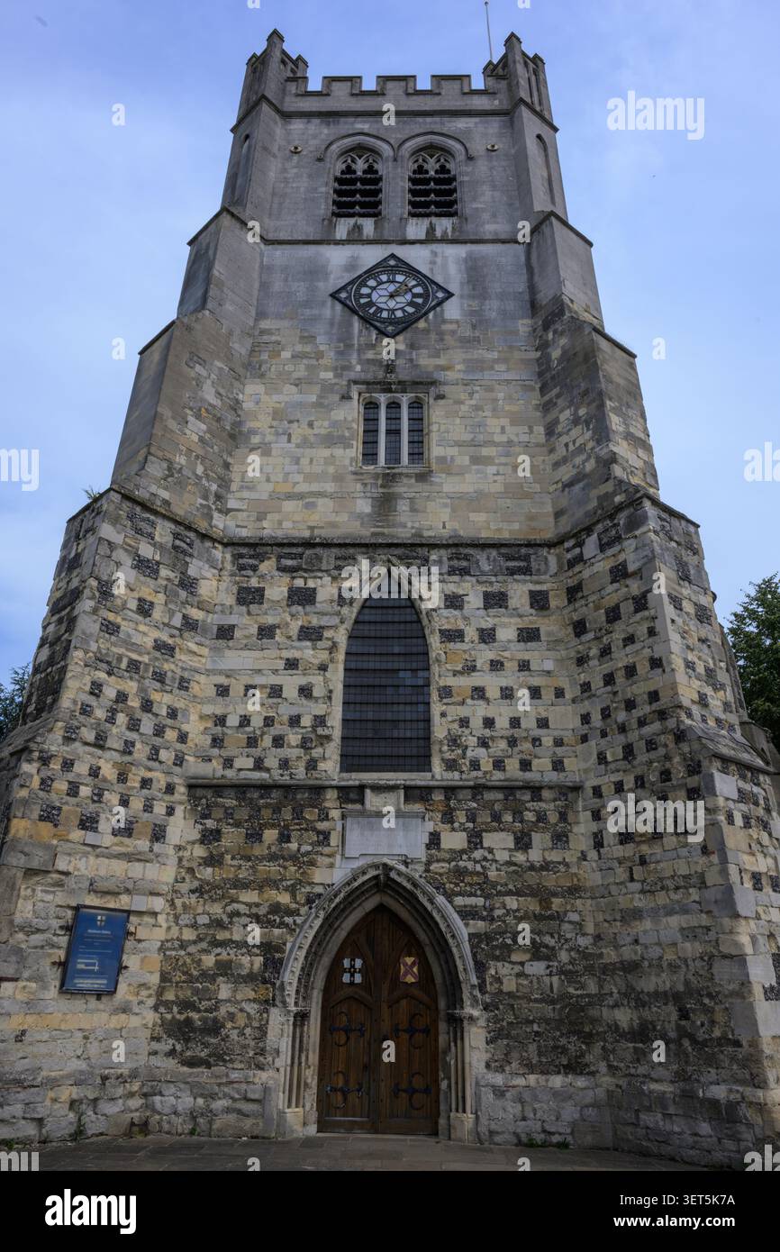 Vue de face de la tour historique de l'église à l'abbaye de Waltham, Essex, montrant l'architecture gothique, le cadran de l'horloge et la porte voûtée sous un ciel bleu. Banque D'Images