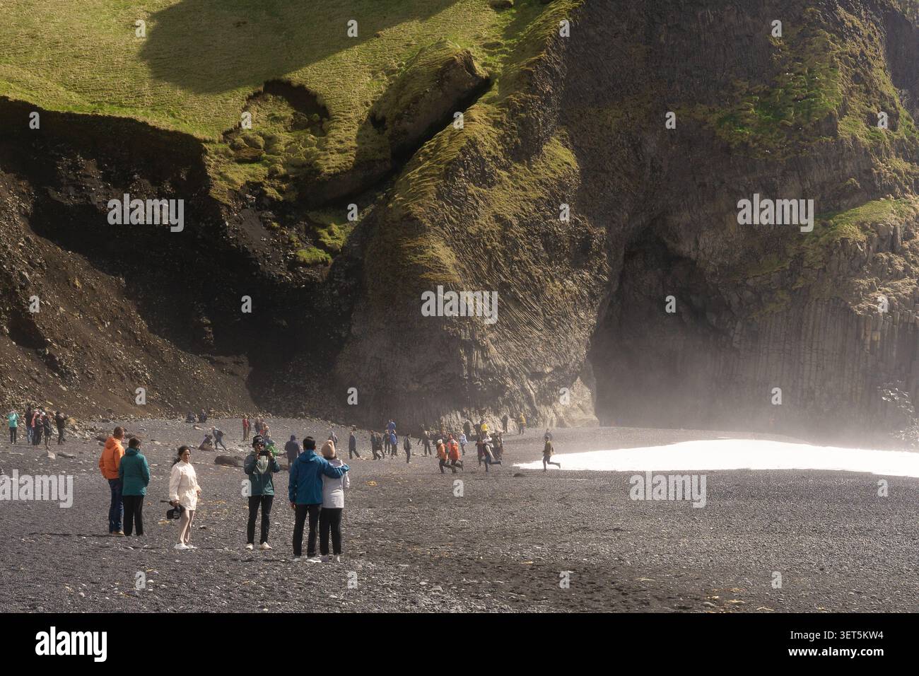 Touristes explorant la plage de sable noir et les falaises de basalte de Reynisfjara près de Vík, dans le sud de l'Islande. Banque D'Images