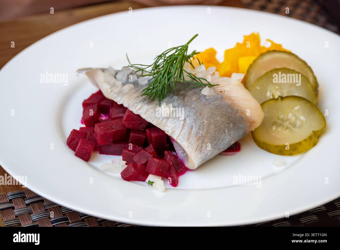 Filet de matjes ou hareng souillé avec dés de betteraves rouges et jaunes, oignons, cornichons marinés et garniture d'aneth, collation estivale rafraîchissante ou casse-croûte de bois Banque D'Images