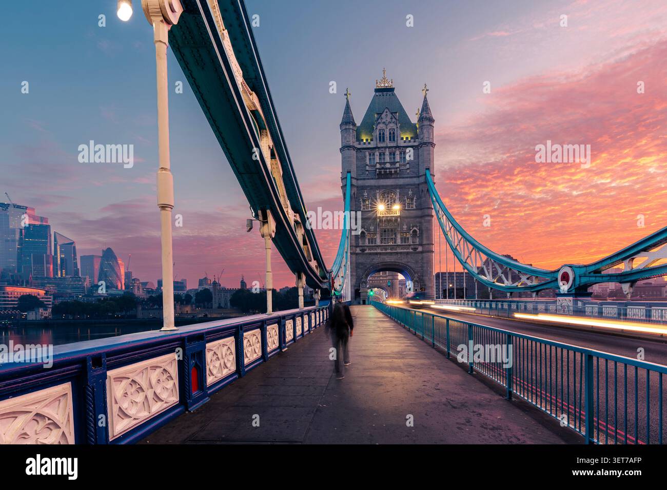 Silhouette floue d'un passager adulte moyen traversant Tower Bridge à Londres pendant le spectaculaire lever du soleil matinal. Destination de voyage européenne, hist Banque D'Images