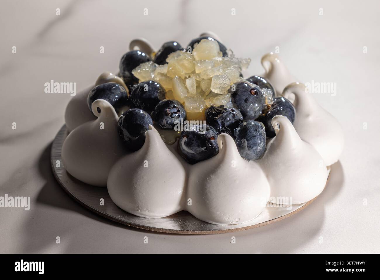 Délicat bleuet citron pavlova. Un éclairage doux met en valeur chaque baie brillante et chaque pic aéré Banque D'Images