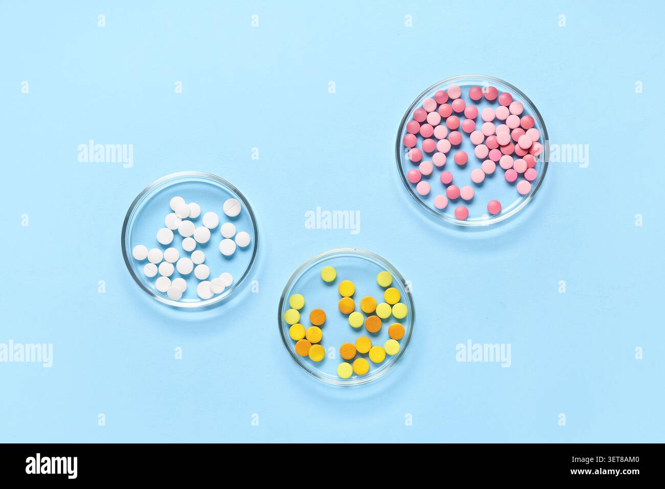 La recherche et le développement pharmaceutiques avec des pilules colorées dans des boîtes de Petri sur fond bleu, la recherche et le développement pharmaceutiques impliquent le s. Banque D'Images
