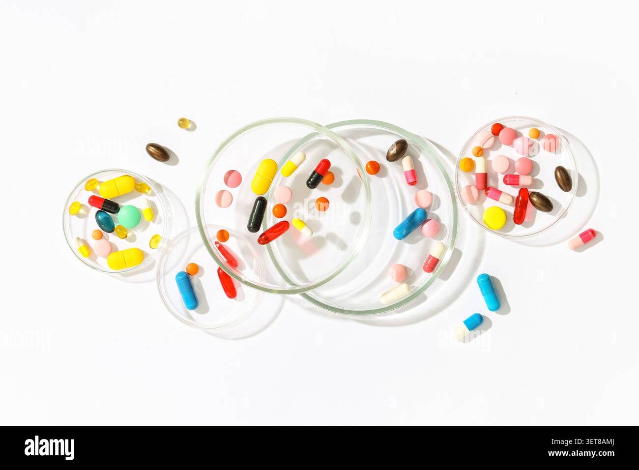 Pilules et capsules pharmaceutiques colorées dans des boîtes de Petri sur fond blanc pour la recherche médicale et les soins de santé Banque D'Images
