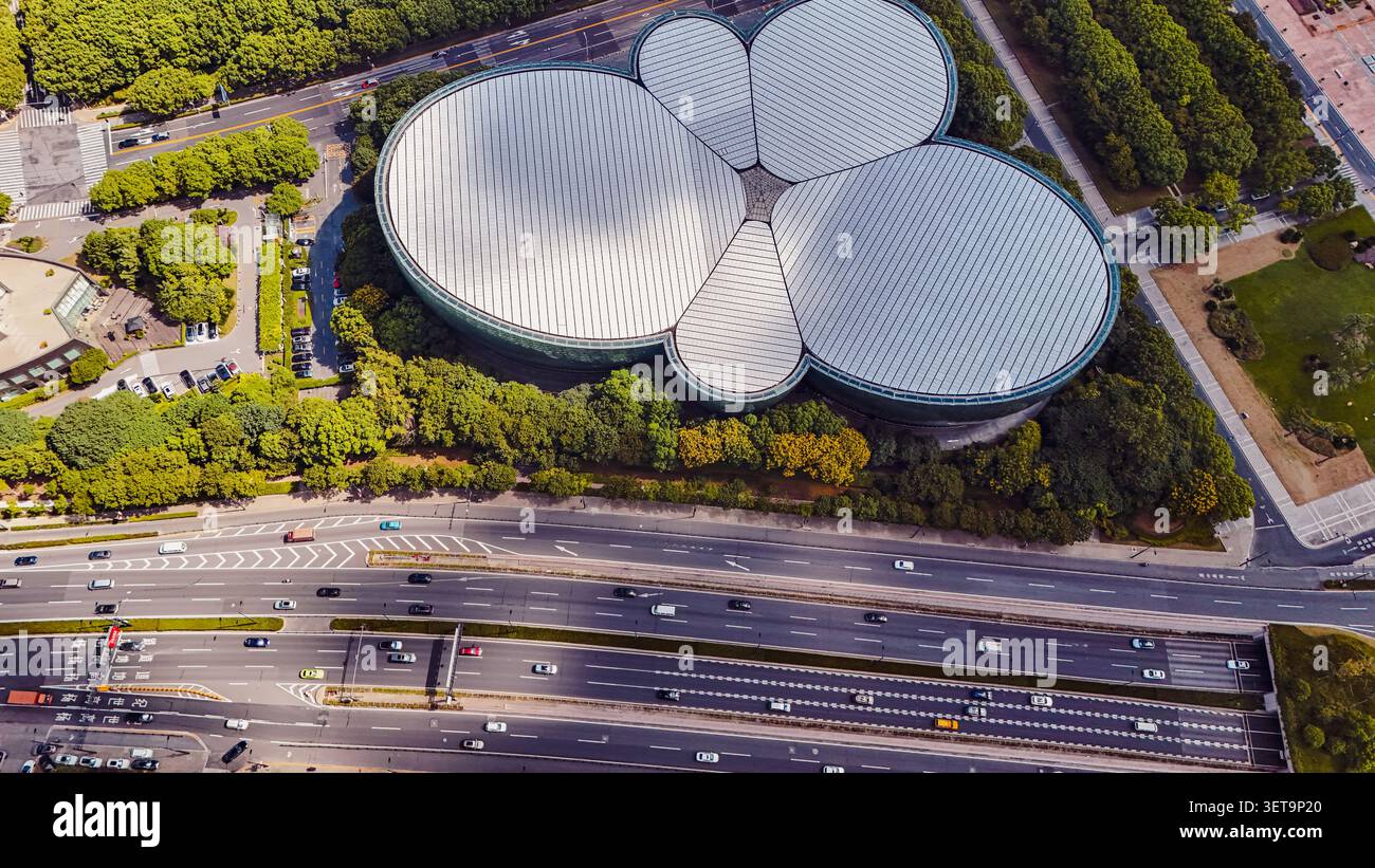Vue aérienne du Shanghai Oriental Art Center avec son toit en forme de pétales distinctif entouré d'arbres verdoyants et une autoroute à plusieurs voies très fréquentée Banque D'Images