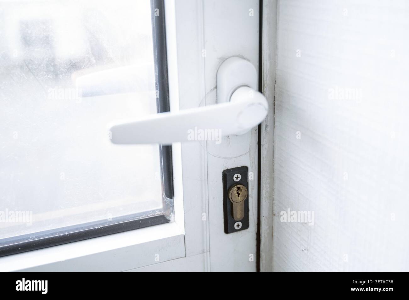 Poignée de porte en plastique blanc, close-up la porte a une fenêtre. Serrure, porte en plastique, bronze. Gros plan d'une porte. Banque D'Images
