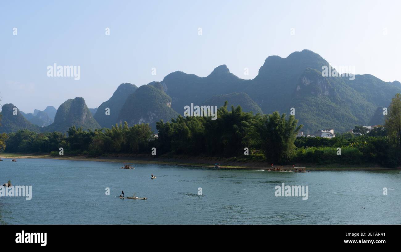 Pêcheurs sur des radeaux de bambou au-dessous d'une gamme de pics karstiques sur la rivière Li, Yangshuo, Guangxi, Chine Banque D'Images