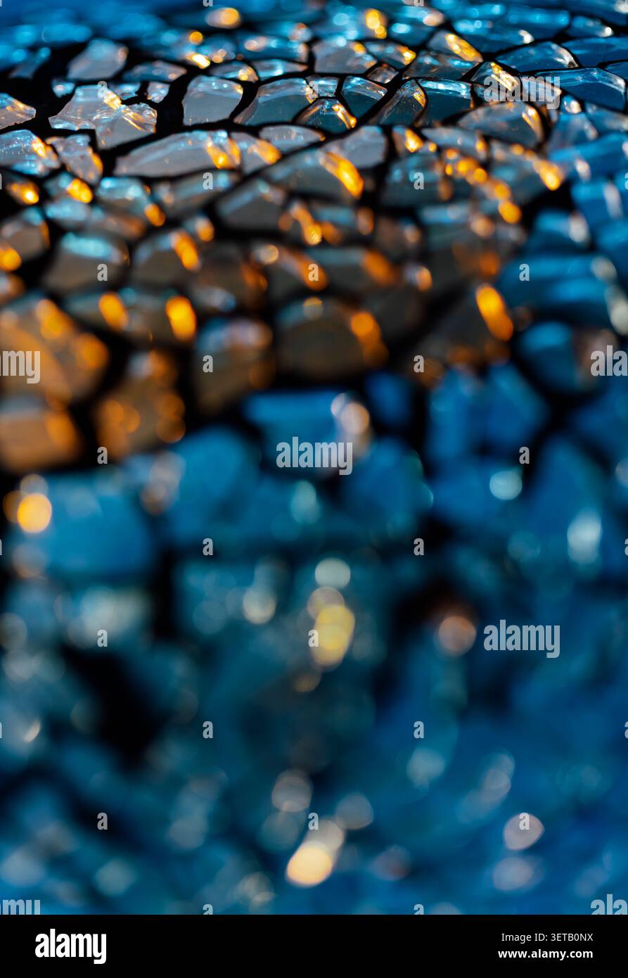 Texture de verre craquelé bleu macro avec lumière dorée chaude et faible profondeur de champ pour fond abstrait Banque D'Images