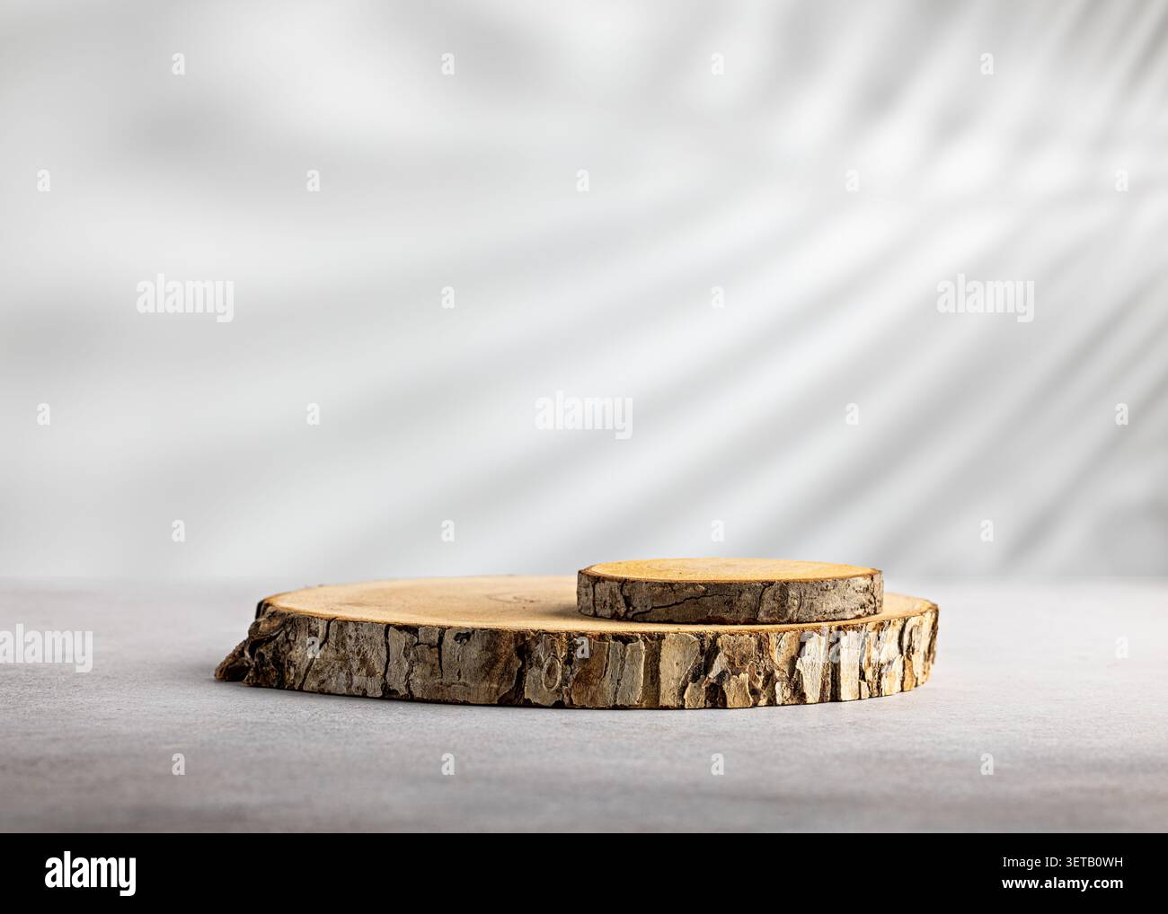 Podium en tranches de bois à deux niveaux avec petite souche surélevée sur fond blanc doux pour une maquette de présentation de produit naturel Banque D'Images