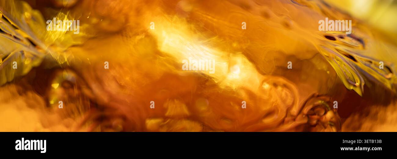 Macro texture panoramique en verre ambré avec réflexion brillante et scintillement chaud pour fond de bannière abstrait de luxe Banque D'Images