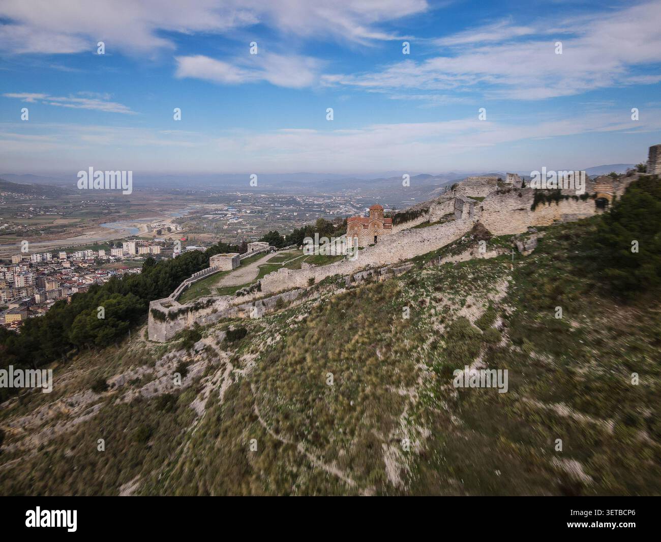 Une photo aérienne capture l'historique château de Berat et l'église Sainte-Trinité au dôme rouge perchée sur une colline, avec la ville de Berat et le Ri d'Osumi Banque D'Images
