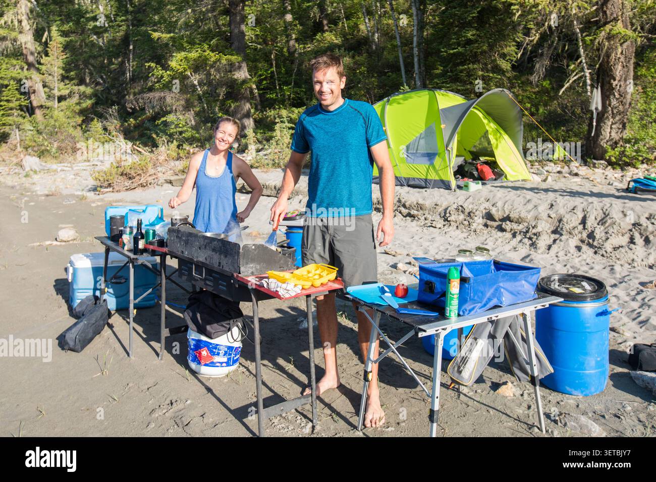 Heureux couple cuisinant le petit déjeuner à leur camping de plage Banque D'Images