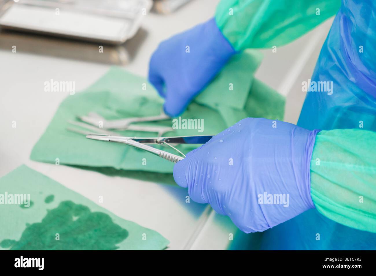 Travailleur de la santé utilisant des pinces en acier dans un environnement d'exploitation, où une préparation précise assure la sécurité du patient et une hygiène professionnelle durin Banque D'Images