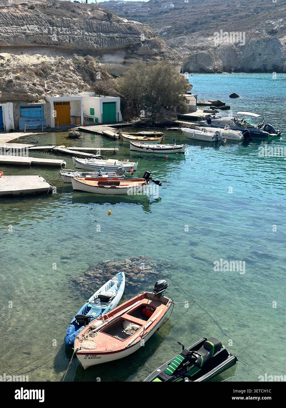 Bateaux de pêche traditionnels amarrés dans les eaux turquoise de Mandrakia, Milos, Grèce. - Image de stock capturée avec un smartphone