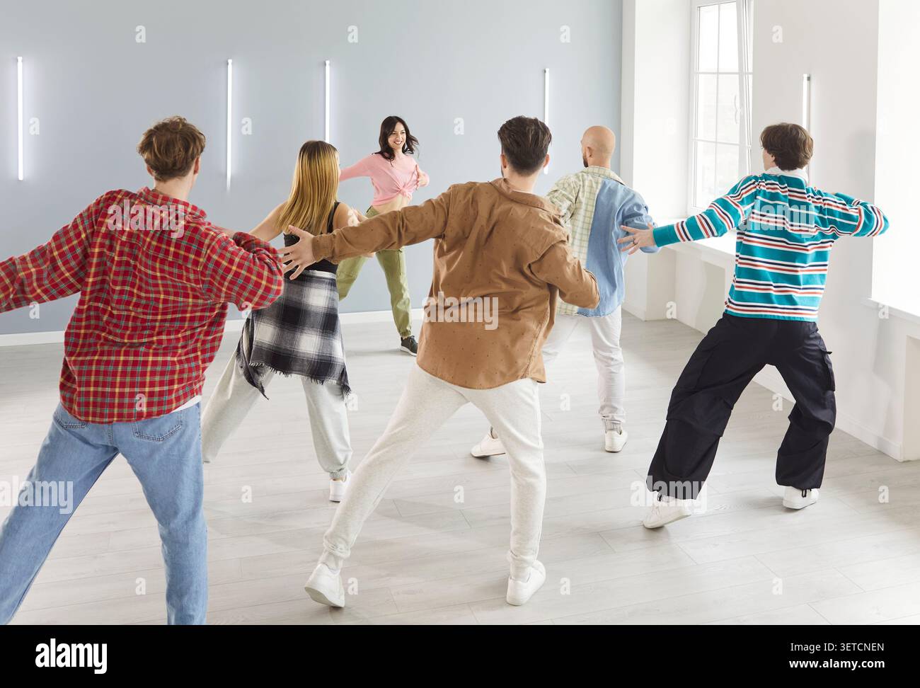 Groupe de danse de personnes dansant activement à l'intérieur, se déplaçant avec un entraîneur en classe Banque D'Images