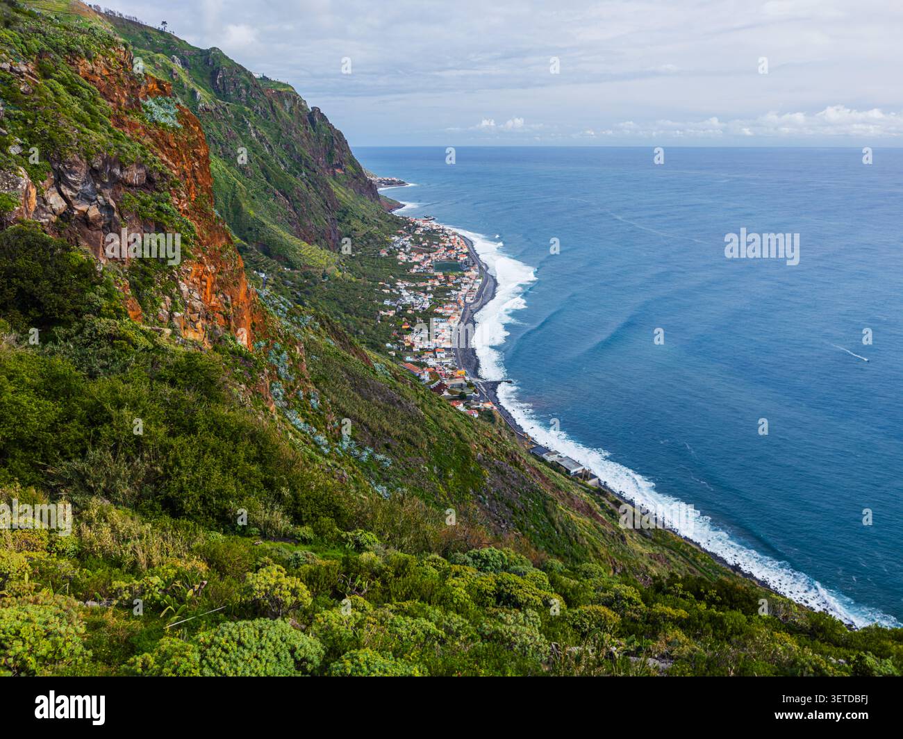 Une photo en grand angle capturant le village côtier de Paul do Mar niché entre d'imposantes falaises verdoyantes et l'océan, Madère, Portugal. Banque D'Images