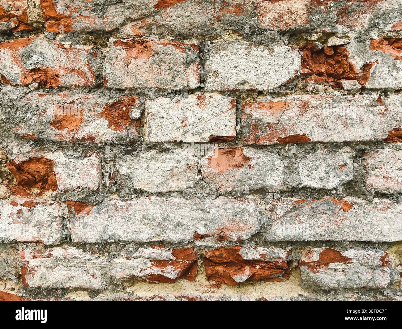 Gros plan d'un vieux mur de briques altérées avec du plâtre fissuré et des briques rouges exposées. Fond rustique de texture de maçonnerie grunge. Banque D'Images