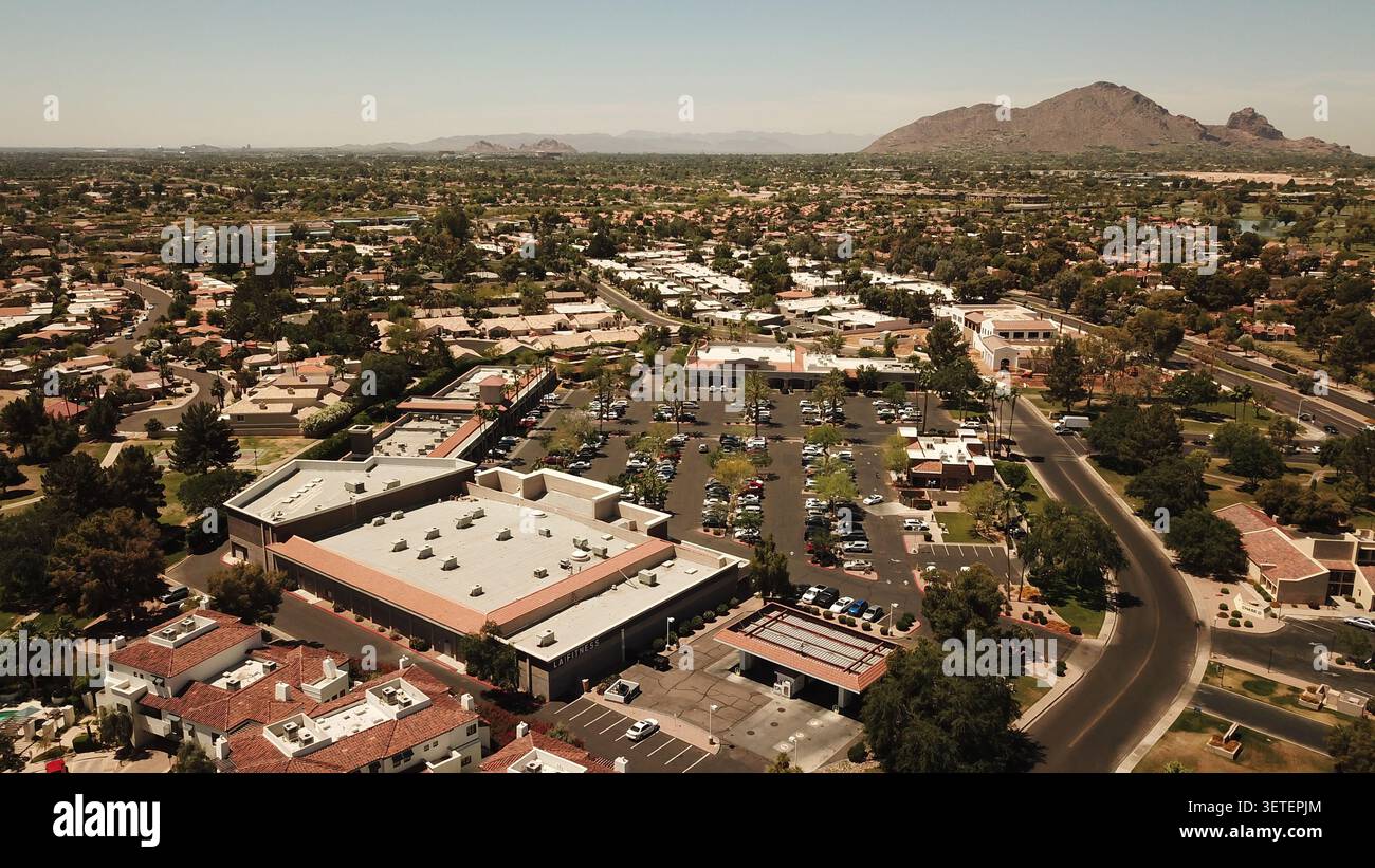 Vue aérienne d'un centre commercial de banlieue avec un club de fitness, un parking, et le quartier résidentiel environnant avec des montagnes désertiques à Phoenix, Banque D'Images