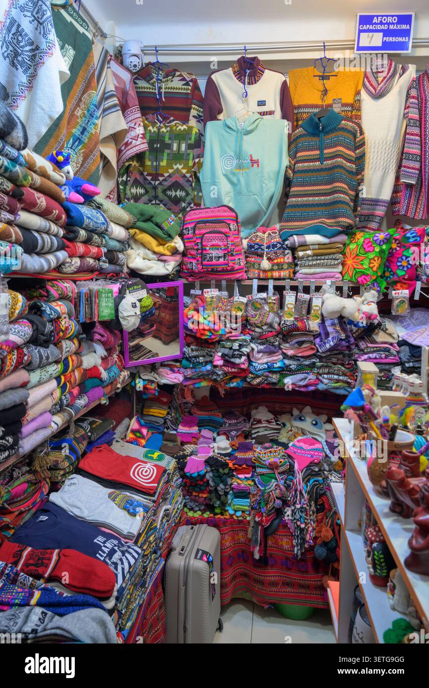Boutique touristique offrant des produits d'alpaga avec des motifs colorés traditionnels dans le centre historique de Cusco, Pérou. Banque D'Images