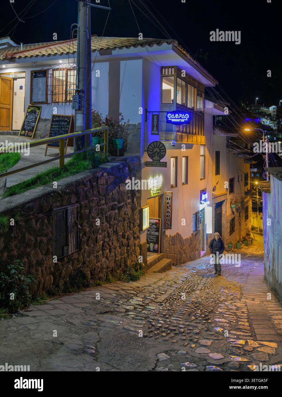 Une seule femme blanche caucasienne marchant tard dans la nuit le long d'une rue étroite et escarpée de Cusco, au Pérou. Banque D'Images