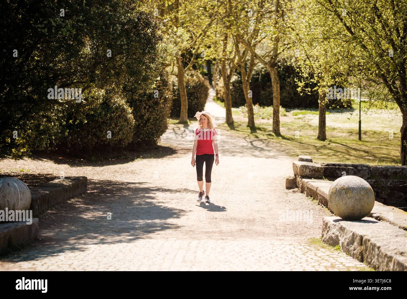 Femme marchant à l'extérieur, profitant d'une promenade paisible dans le parc à la lumière du soleil Banque D'Images