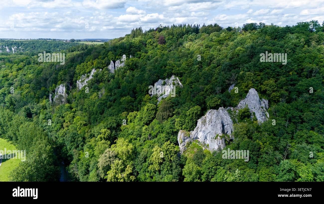 Vue aérienne des falaises calcaires de la via Ferrata Pont-a-Lesse s'élevant d'une forêt dense et verdoyante sous un ciel nuageux à Dinant, région wallonne, Belgiu Banque D'Images