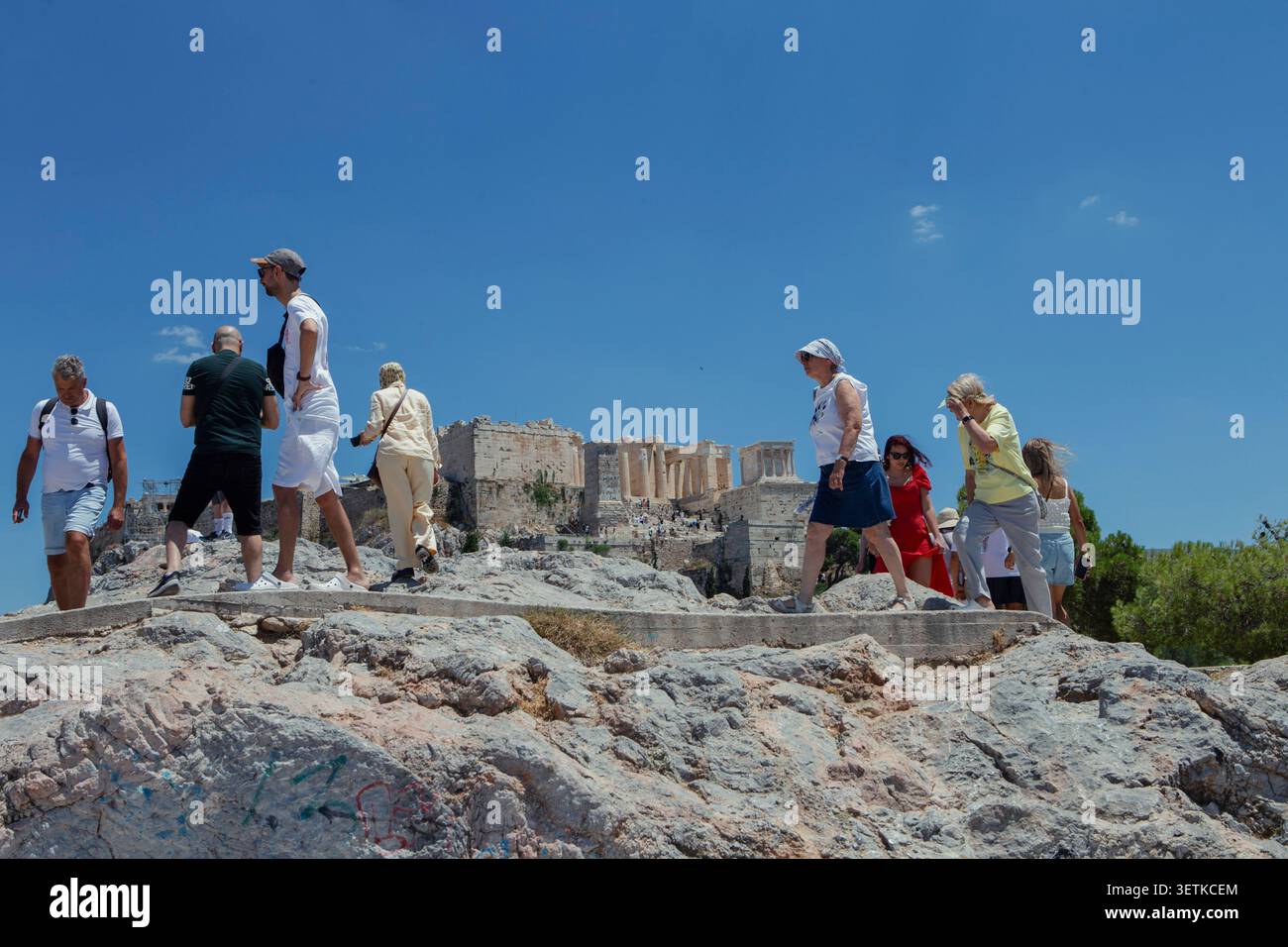 Athènes, Grèce. 21 juin 2026. Les touristes traversent la colline d'Aréopage surplombant l'Acropole à Athènes, en Grèce, le 21 juin 2026. L'Acropole, site classé au patrimoine mondial de l'UNESCO, est l'un des monuments archéologiques les plus visités de Grèce. Athènes attire des millions de touristes chaque année, en particulier pendant la saison estivale, malgré les périodes de chaleur extrême. (Photo de Elvis Takahashi Mantello/Middle East images/StringersHub/SIPA USA) crédit : SIPA USA/Alamy Live News Banque D'Images