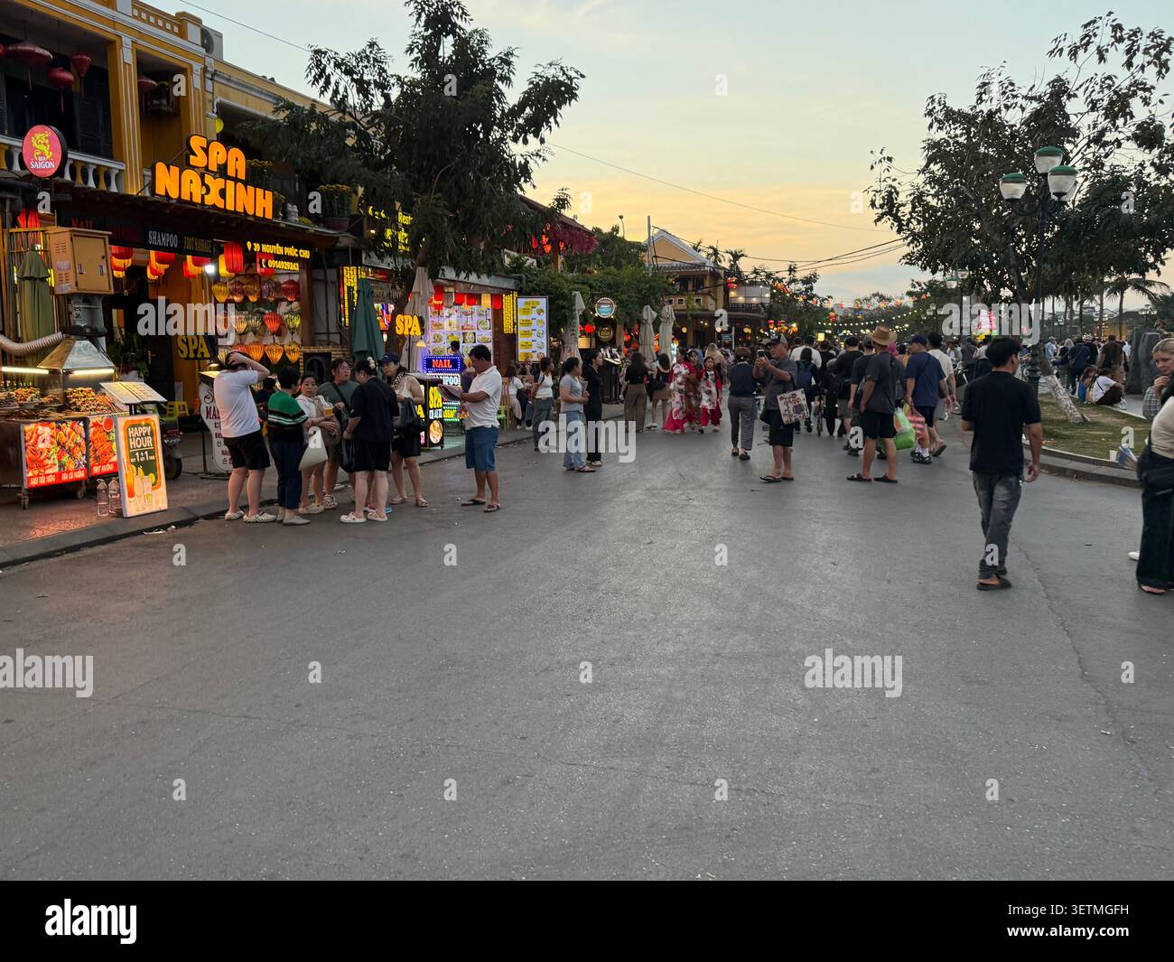 Au crépuscule, alors que les visiteurs affluent dans Nguyen Phuc Chu, une longue rue piétonne à côté de la rivière Thu bon dans la vieille ville de Hoi an dans la province de Quang Nam, centra - Image de stock capturée avec un smartphone