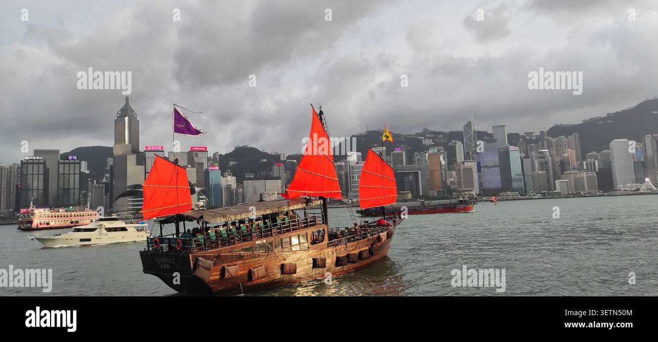 HONG KONG - 18 JUILLET 2023 : le bateau à voile rouge Aqua Luna traverse le port Victoria au crépuscule. Banque D'Images