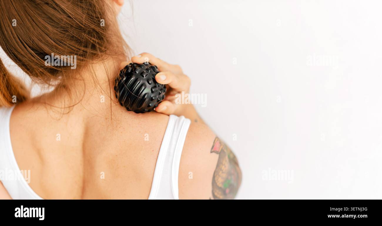 Femme utilisant la boule de massage pour le cou haut du dos Banque D'Images