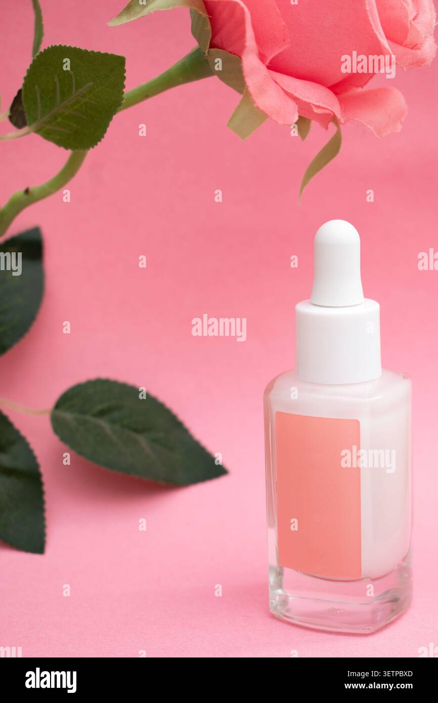 Bouteille de sérum cosmétique rose avec compte-gouttes sur fond rose pastel, concept de soins de la peau Banque D'Images