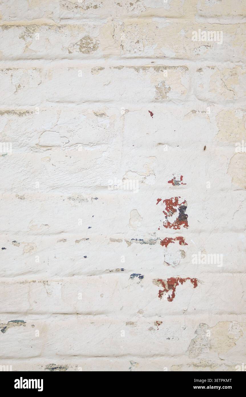 Vieux mur de briques peintes avec peinture blanche fissurée et maçonnerie apparente. Texture grunge industrielle avec espace de copie. Banque D'Images
