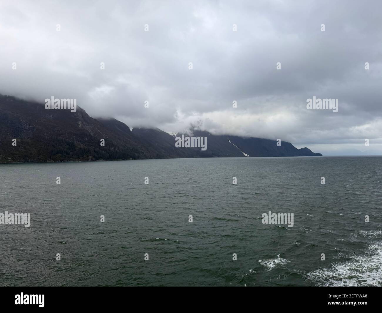 La côte rocheuse et montagneuse du parc national de Glacier Bay, par une journée très nuageuse et brumeuse, au printemps, en Alaska, aux États-Unis - Image de stock capturée avec un smartphone