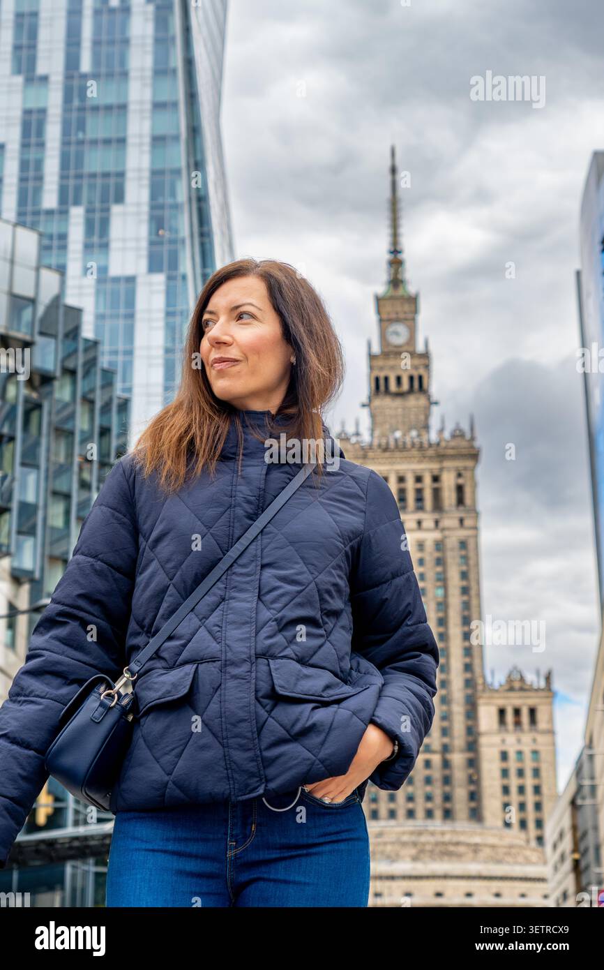 Jeune femme caucasienne dans la veste en duvet marine avec Palais de la culture et de la science fond Banque D'Images