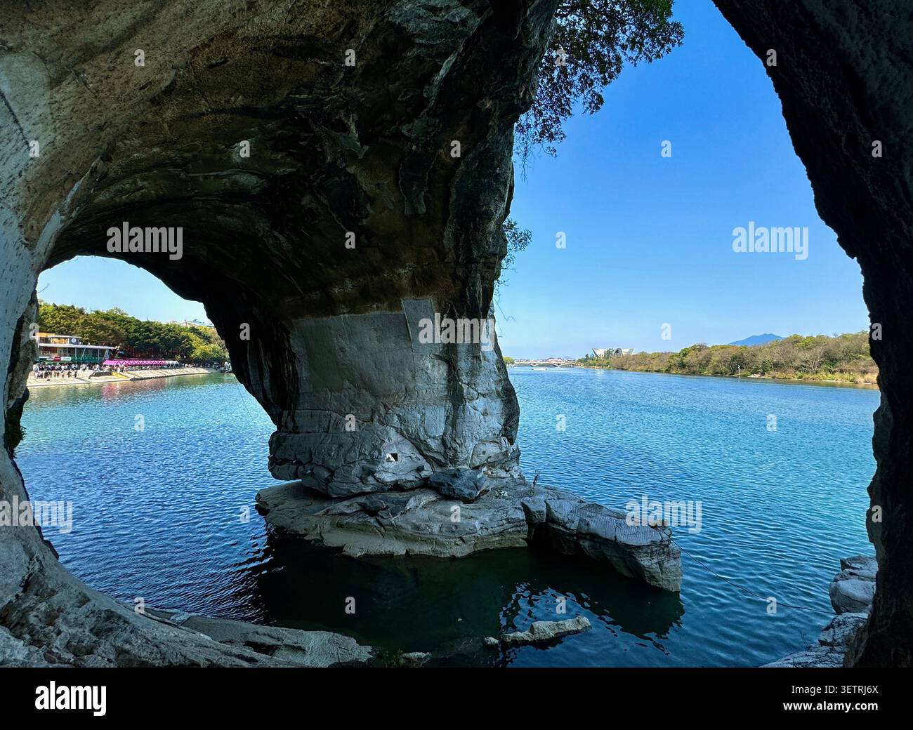 Vue à travers l'arc de la grotte rocheuse naturelle de la rivière Li et le paysage karstique à Elephant Trunk Hill Water Moon Cave, Guilin, Guangxi, Chine - Image de stock capturée avec un smartphone