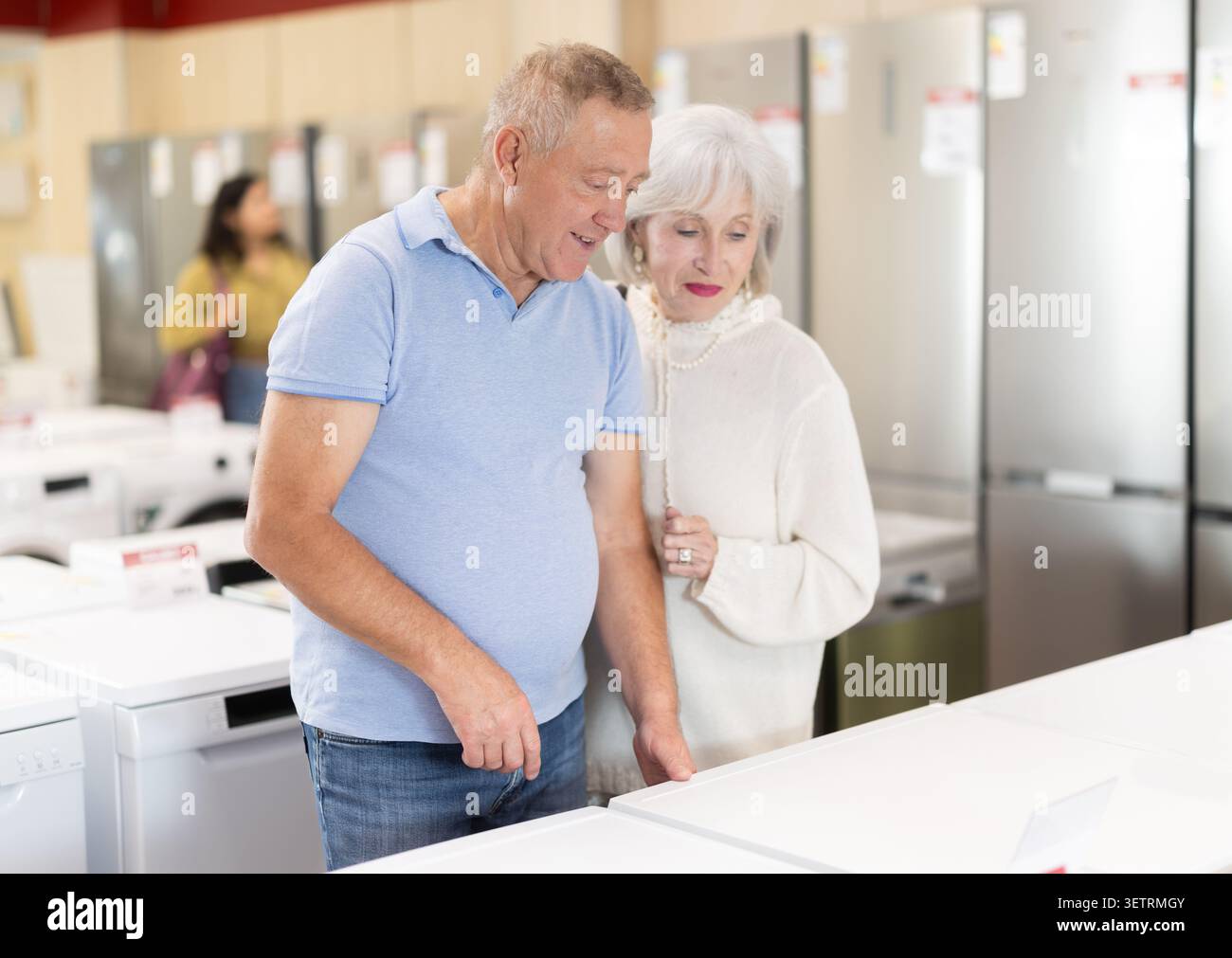 Couple de personnes âgées choisissant une machine à laver dans un magasin Banque D'Images