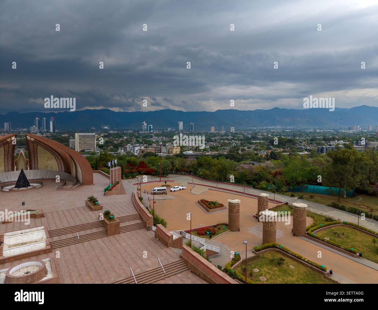 Vue aérienne du monument du Pakistan avec sa structure en forme de pétales, sa place environnante et sa végétation luxuriante surplombant le paysage urbain d'Islamabad, Isl Banque D'Images