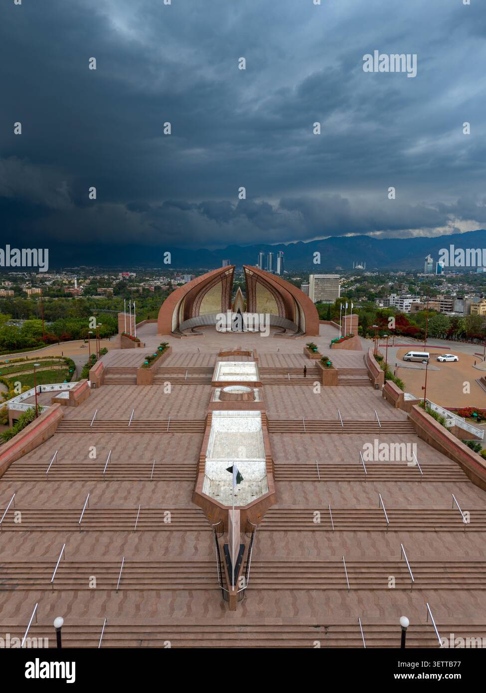 Vue aérienne du monument du Pakistan avec sa structure en forme de pétales distinctive, sa place en pierre et le parc environnant sous un ciel orageux spectaculaire Banque D'Images