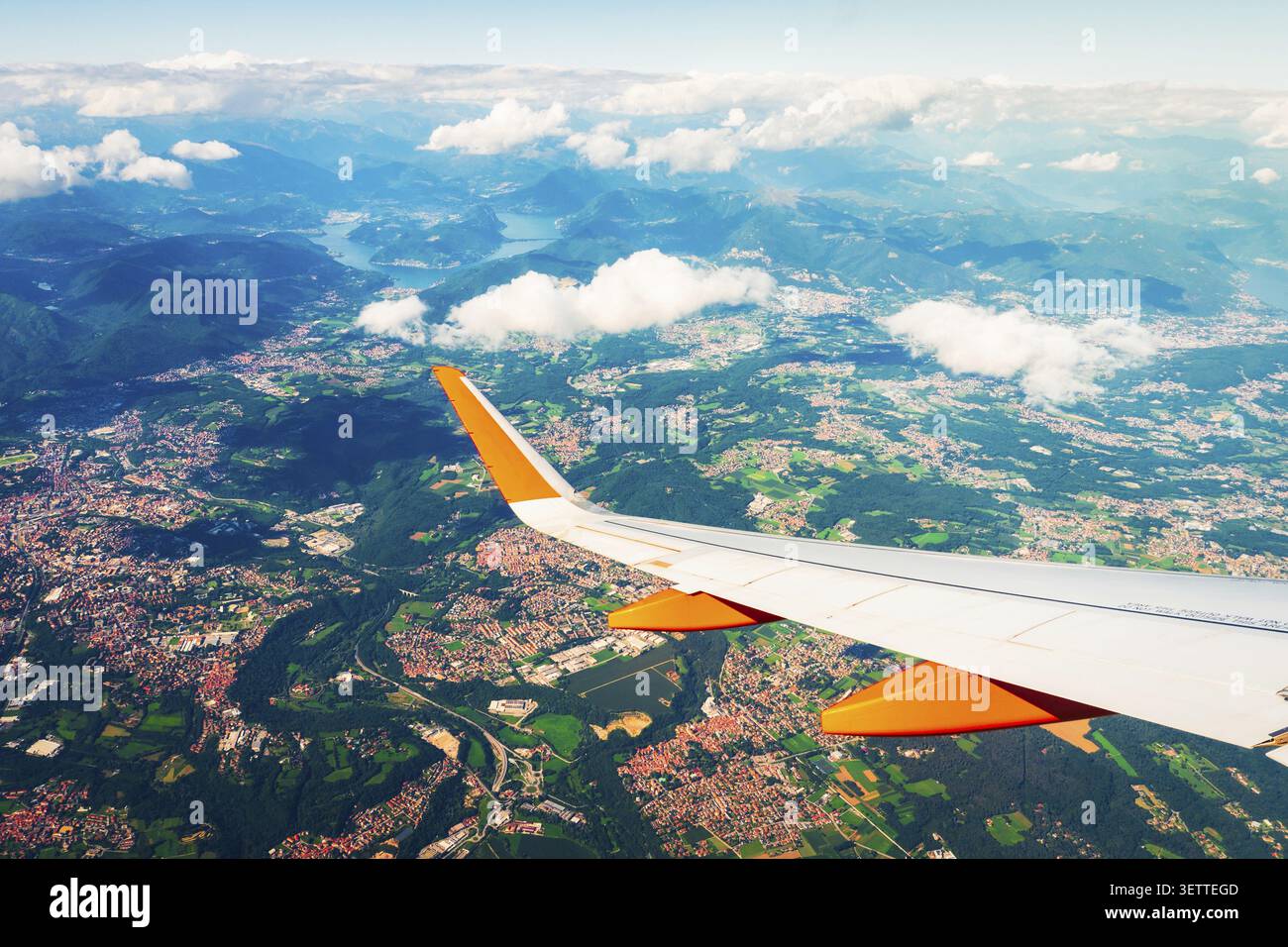 Point de vue du siège passager d'un avion commercial aérien au décollage. Aile d'avion au-dessus des terres agricoles des villes et des montagnes vues à travers la victoire de l'avion Banque D'Images